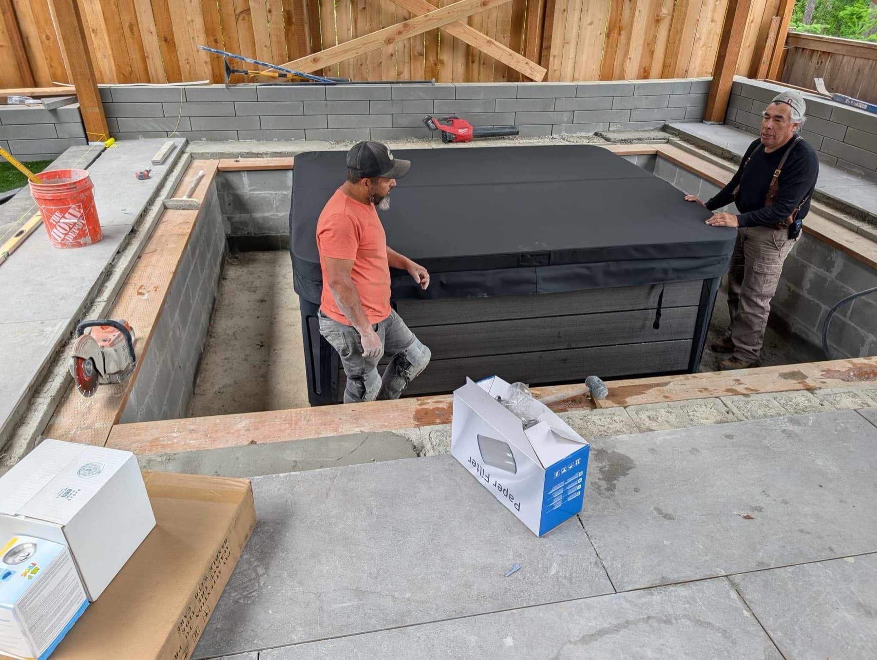 Crew setting a hot tub into a sunken block enclosure