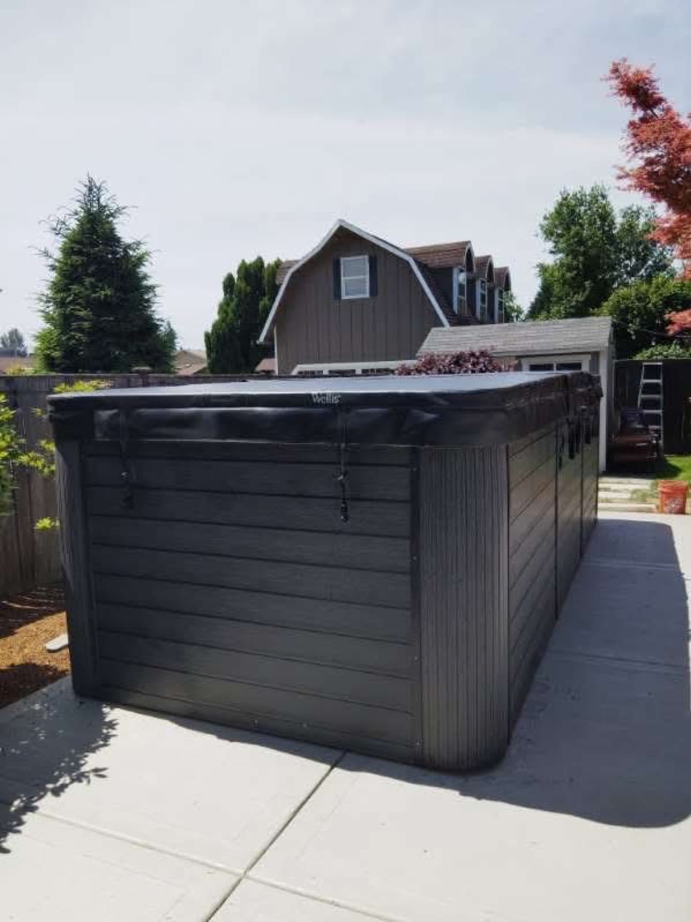 Wrapped hot tub delivered onto a concrete pad beside the house