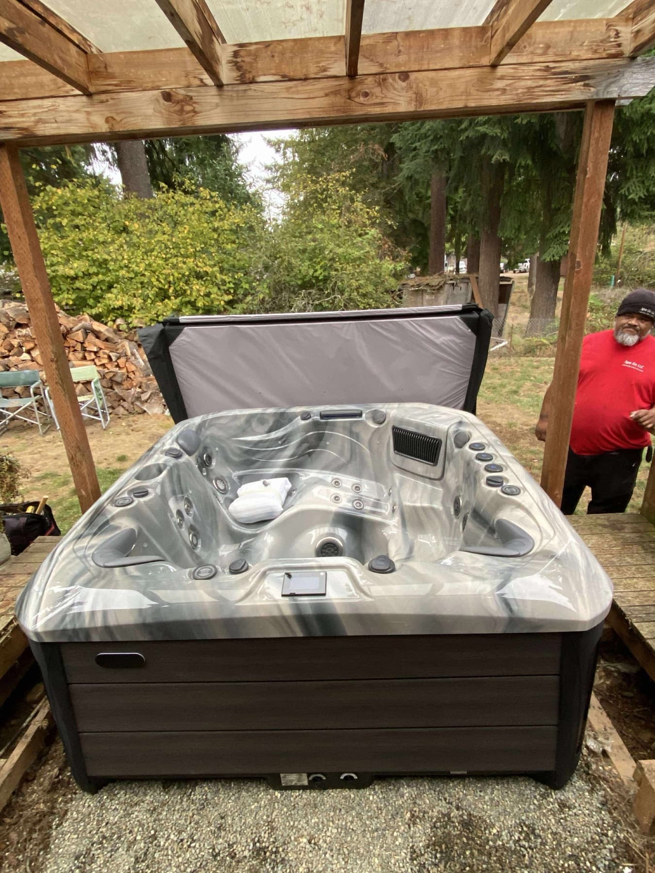 Hot tub with the cover open beneath a wood pergola