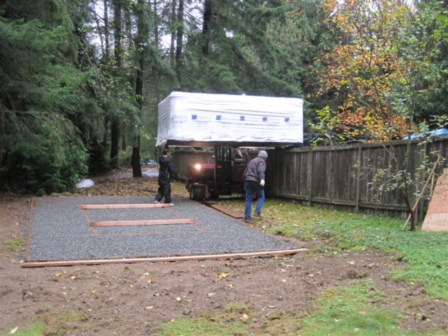 Crew delivering a hot tub along a gravel path to a side yard