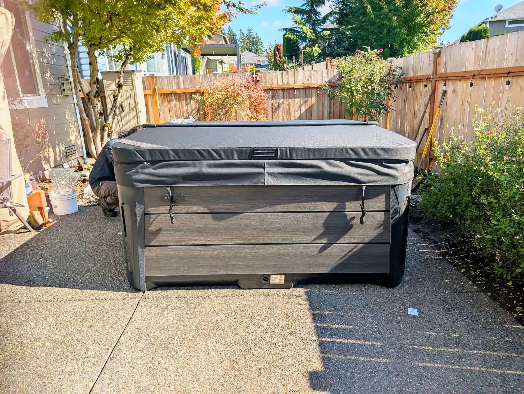 Hot tub with the cover closed in a fenced backyard