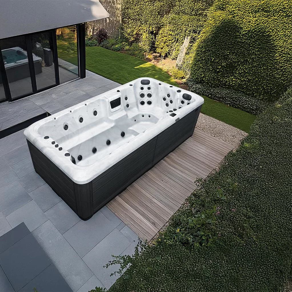 Platinum Spas Titan swim spa on a patio beside a modern home and garden